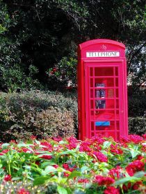 An old fashioned red phone booth and lush landscape at the United Kingdom pavillion inside EPCOT.